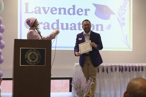 Meegs Longacre hands Jimmy Luckman his certificate and lavender cord during Lavender Graduation, a ceremony for graduating LGBTQIA+ students at Syracuse University.