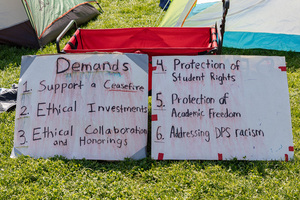 Protestors at Syracuse University's Gaza Solidarity encampment display posters with their six demands from the university.
