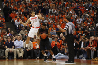 Syracuse guard Brandon Triche attempts to block a shot, as Cincinnati guard JaQuon Parker tries to duck under him.