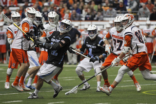 The Syracuse defense looks on as a John Hopkins attack fires a shot.