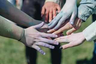 Attendees at the South Asian Student Association's (SASA) Holi event huddled together to showcase their hands covered in color powder.